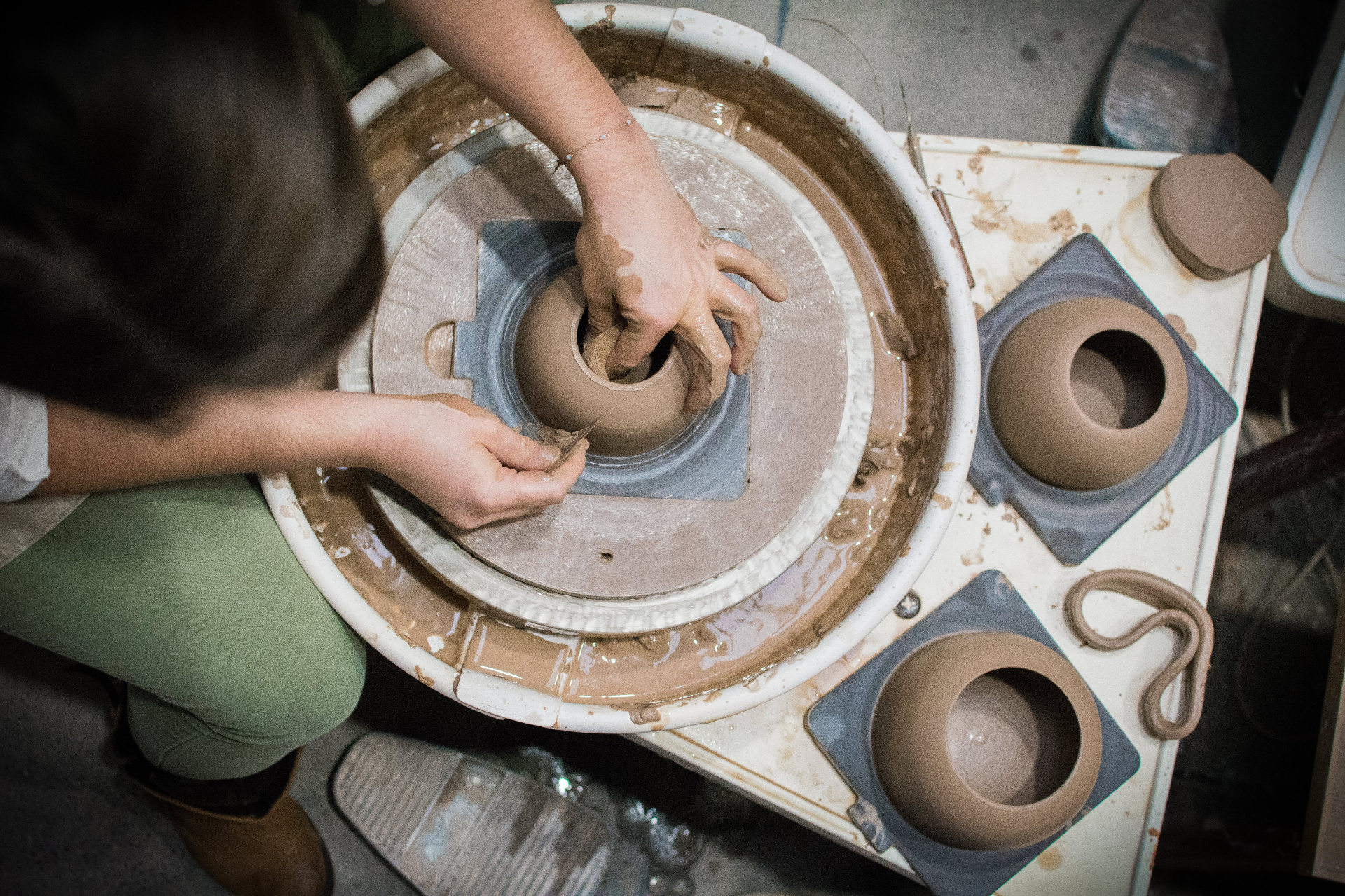 Overhead view of the maker trimming a vessel while newly formed bowls sit nearby